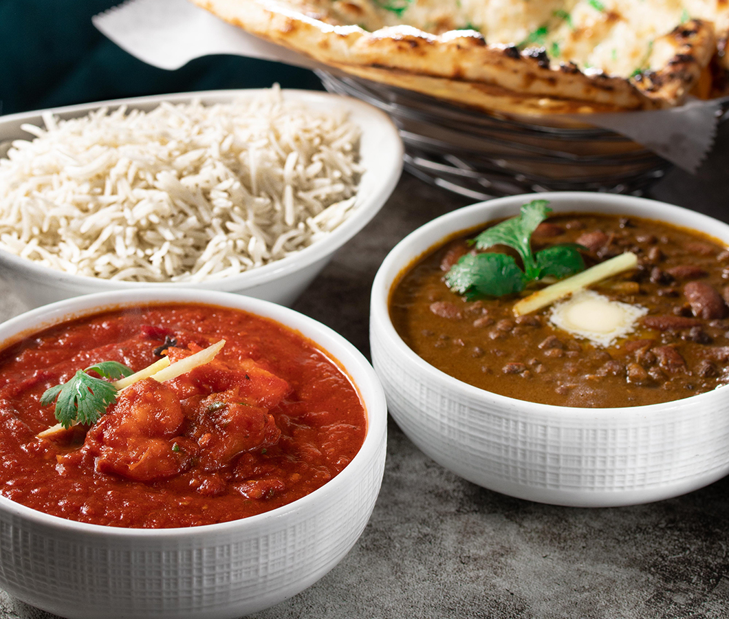 Butter chicken and dal makhani with basmati rice and a basket of fresh naan