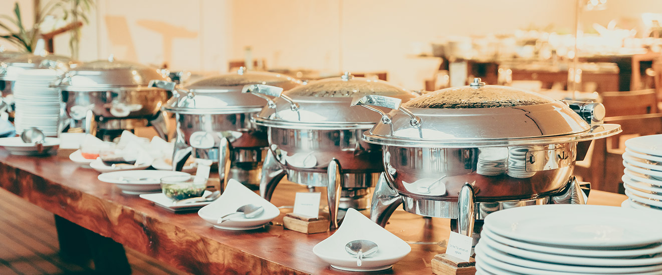 Polished chafing dishes and plates set up along the buffet counter