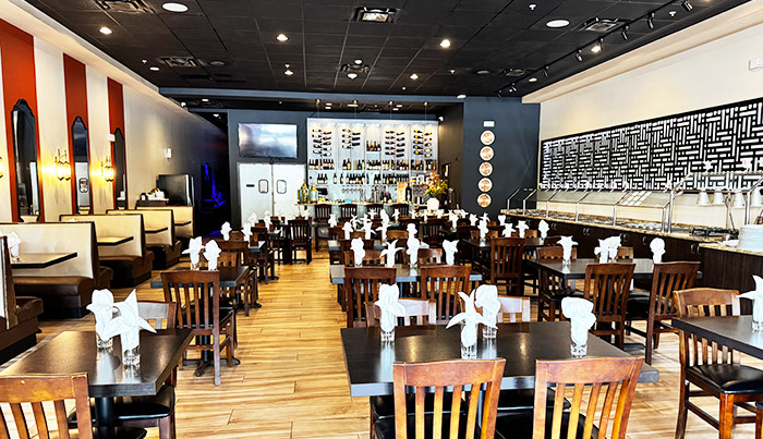Bombay Grove dining room looking toward the bar, with striped coral walls and set tables