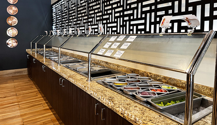 Close view of the Bombay Grove buffet line with warming trays and chilled condiments