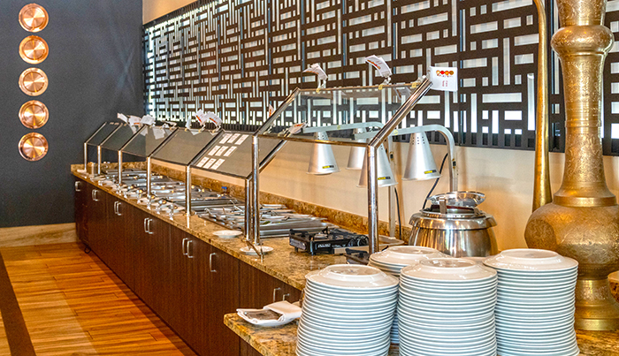 Buffet line with warming stations, stacked plates and a brass urn