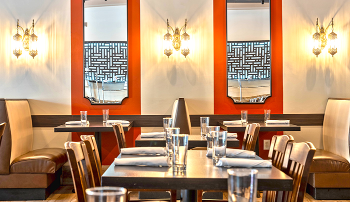 Banquette seating with arched mirrors and brass sconces in the Bombay Grove dining room