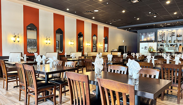 Arched mirrors and brass sconces along the striped wall of the Bombay Grove dining room
