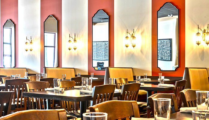 Bombay Grove dining room with warm coral walls, mirrors and set tables