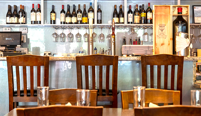 Bar seating with hanging glassware and the wine wall at Bombay Grove